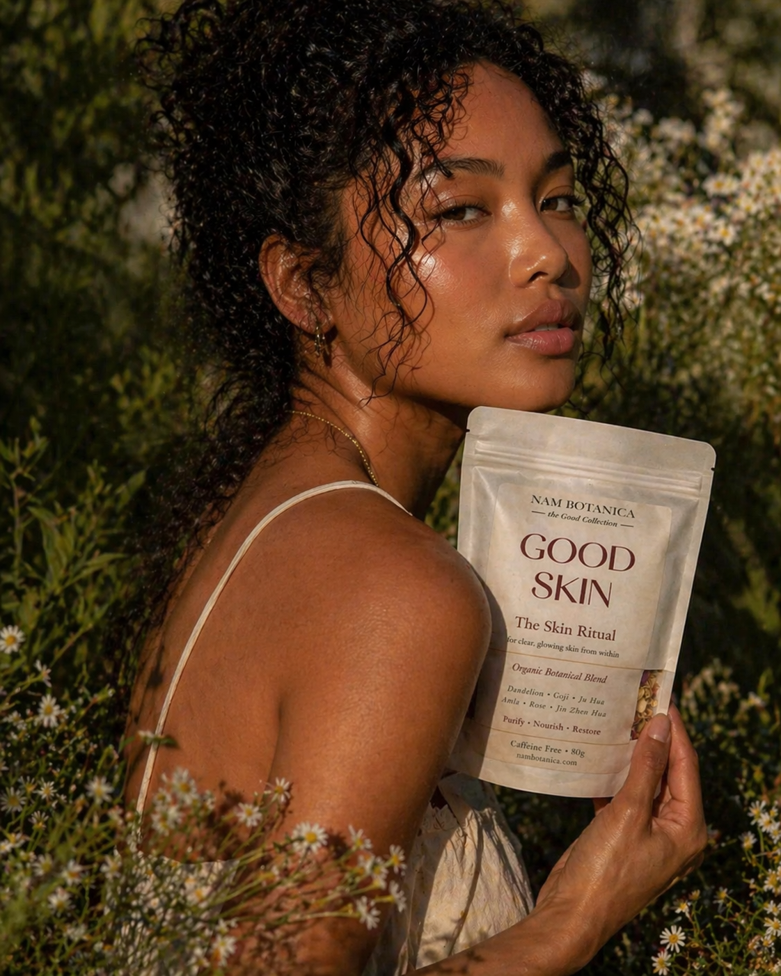 Nam Botanica Good Skin Tea – woman with clear glowing skin holding The Skin Ritual organic botanical blend, caffeine free herbal tea for skin health and traditional Chinese medicine